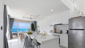 A modern kitchen with a central island, stainless steel appliances, and a view of the ocean. - Villa the wave (Koh Samui)