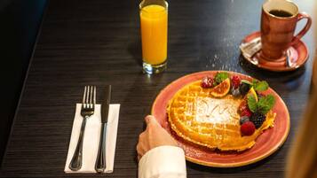 A breakfast setting with a plate of food, a glass of orange juice, and a cup of coffee on a table.