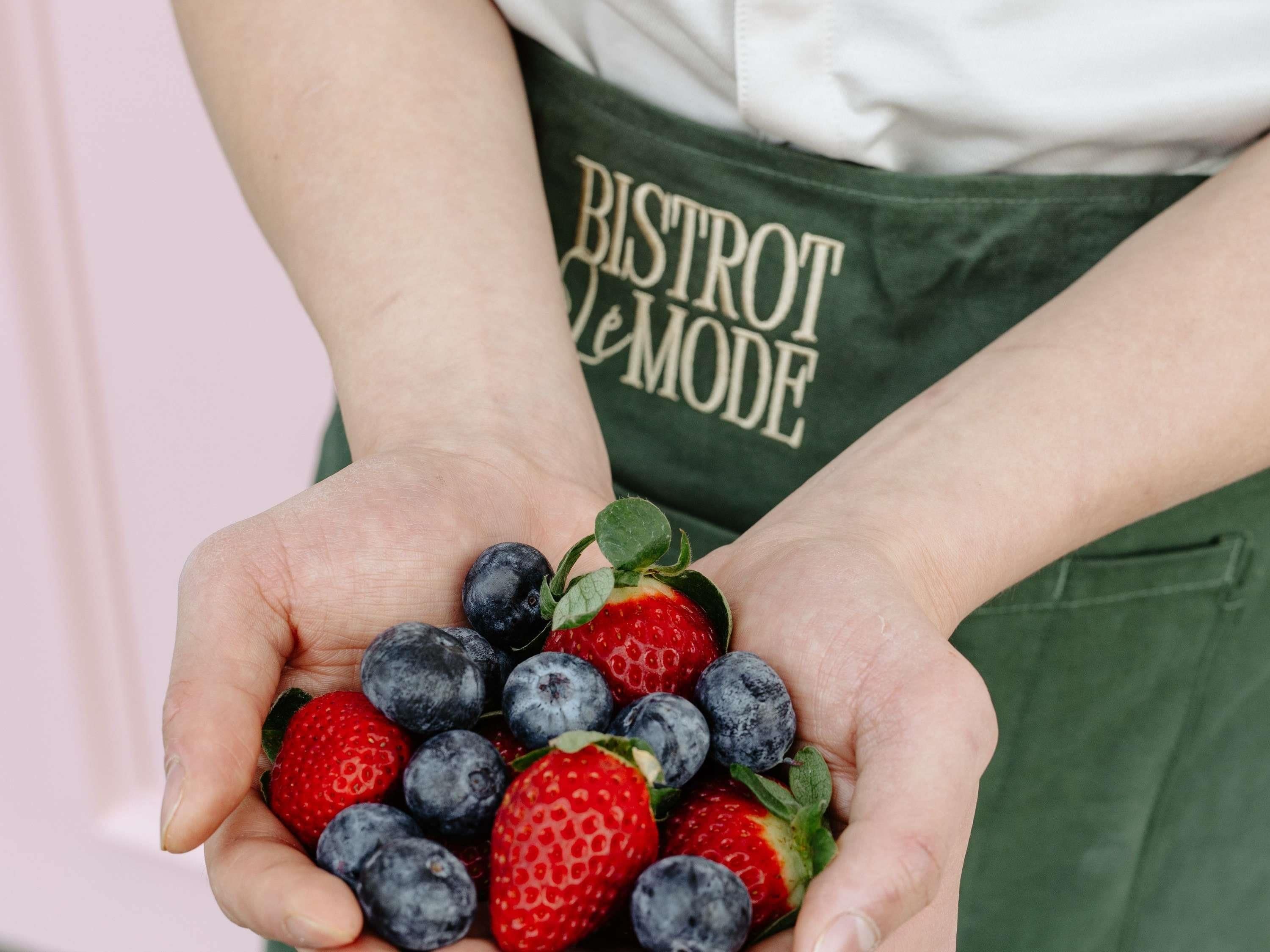 Una persona sosteniendo un racimo de fresas y arándanos.