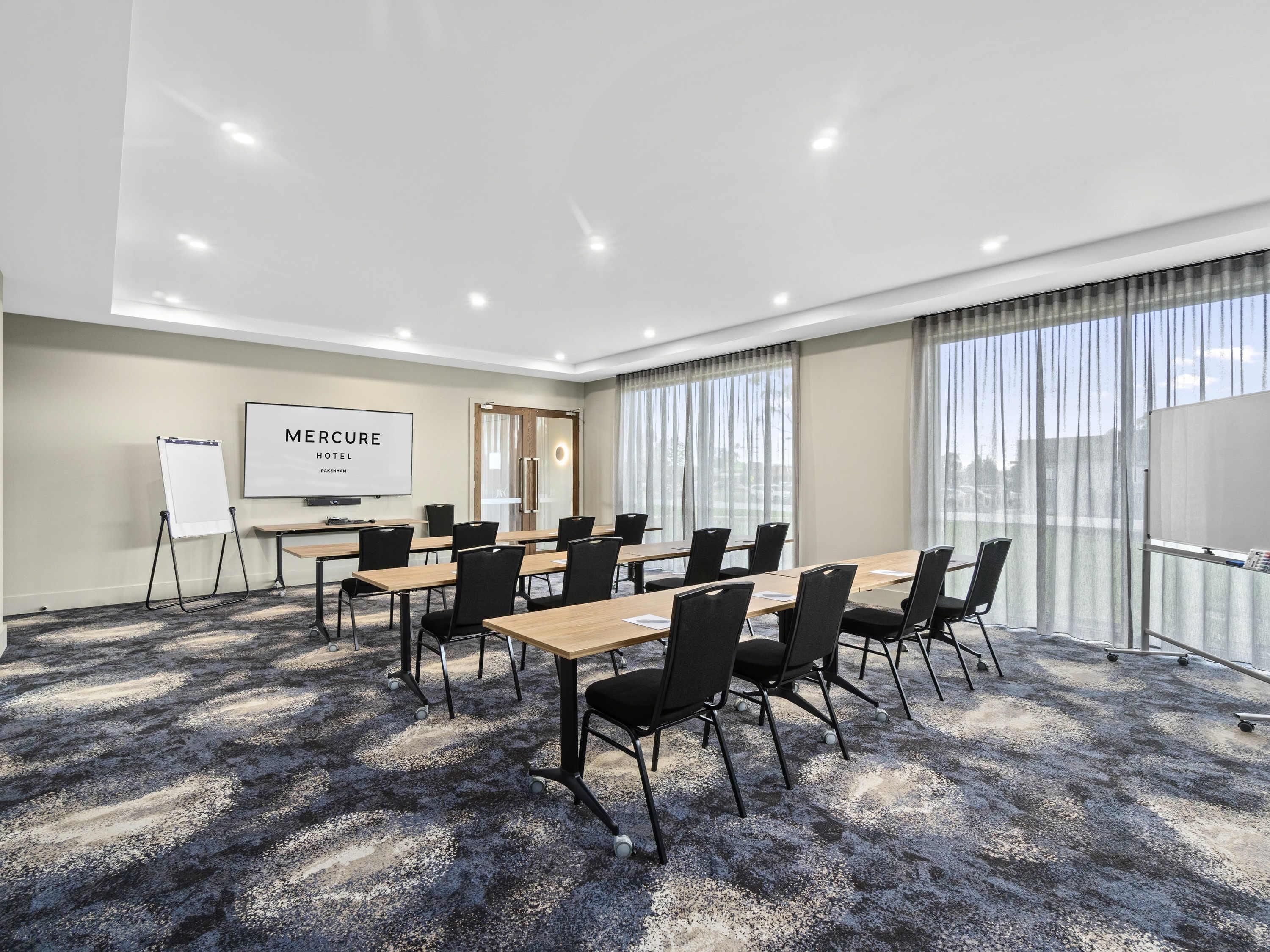 A conference room with a large table, chairs, a whiteboard, and a presentation screen.