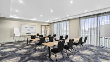 A conference room with a large table, chairs, a whiteboard, and a presentation screen.