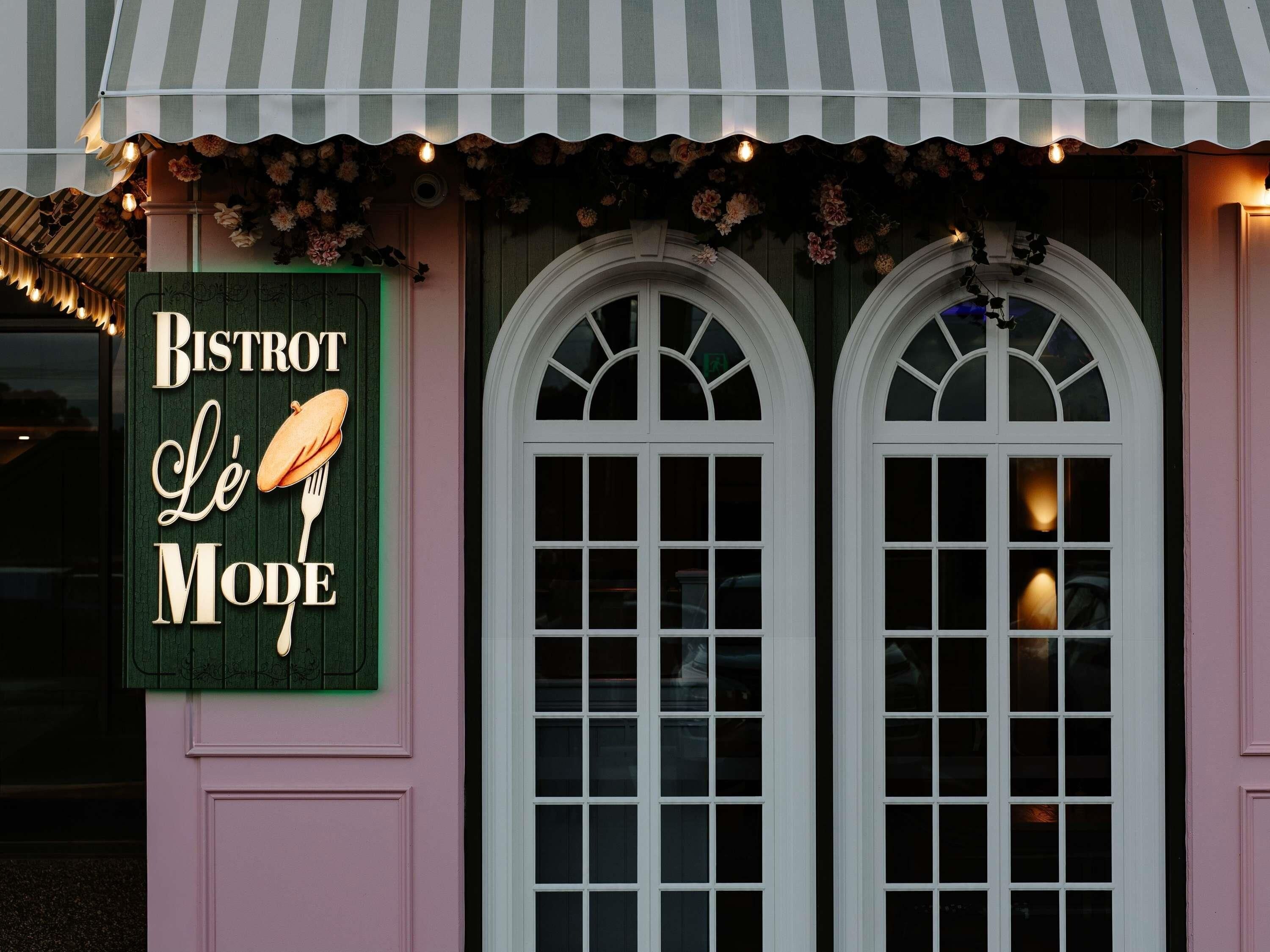 Un edificio con un letrero que dice 'BISTROT Le Mode' y dos ventanas de arco.