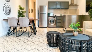 A modern kitchen with stainless steel appliances, a dining area with a table and chairs, and a patterned floor.