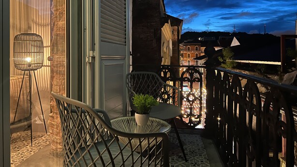 A balcony with a chair, a small table, and a potted plant.