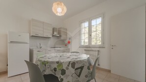 A compact kitchen with a dining area, featuring a modern refrigerator, a stove, and a dining table with chairs.