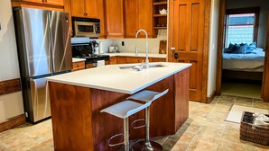 A kitchen with wooden cabinets, a stainless steel refrigerator, a microwave, and a sink. - Luxurious TRUE ski in/out chalet in Happy Valley with gorgeous views! (Beaverdell)