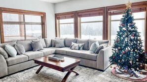 A living room with a sectional sofa, a coffee table, and a Christmas tree. - Luxurious TRUE ski in/out chalet in Happy Valley with gorgeous views! (Beaverdell)