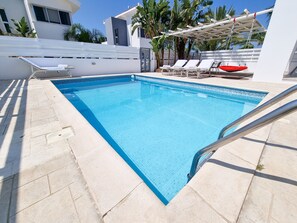 Relax by the pool surrounded by lounge chairs and a shaded pergola.