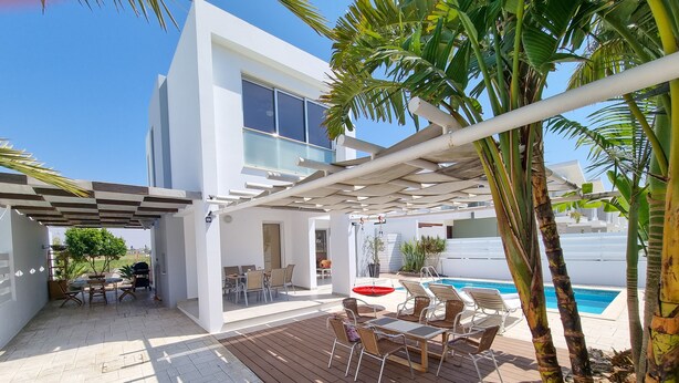 Une terrasse extérieure moderne avec une piscine, une plateforme en bois et un espace salon.