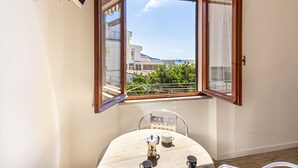 A room with a corner window overlooking a balcony, a table with chairs, and a flat-screen TV mounted on the wall. - Casa Bartolomea - CASA BARTOLOMEA 8 (Campo nell'Elba)