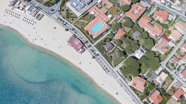 An aerial view of a coastal area with a beach, residential buildings, and a swimming pool. - Casa Bartolomea - CASA BARTOLOMEA 8 (Campo nell'Elba)