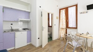 A compact kitchen with a refrigerator, stove, and sink, adjacent to a dining area with a table and chairs. - Casa Bartolomea - CASA BARTOLOMEA 8 (Campo nell'Elba)