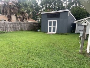 Enjoy a serene outdoor space surrounded by lush trees and shrubs, featuring a charming shed and a birdhouse.