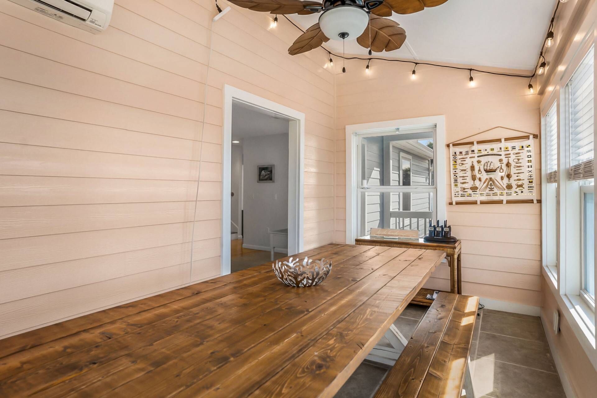 A room with a wooden table, a ceiling fan, and a wall-mounted light fixture.