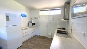 A compact kitchen with white cabinets, a microwave, a sink, and a window above the door. - Getaway Villas Unit 38-7 - comfort on a budget (EXMOUTH)