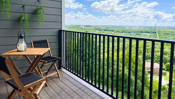 Eine Holzterrasse mit Tisch und Stühlen, einem hängenden Blumentopf und einer Laterne.