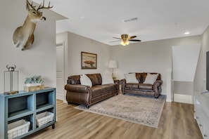 A living room with two brown leather sofas, a blue shelving unit, a mounted deer head, a ceiling fan, and a patterned rug. - 5 min to Branson Strip, 8 min to SDC, Panoramic View! (Branson)