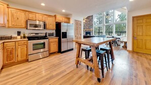 A spacious kitchen with wooden cabinets, stainless steel appliances, and a large island with stools. - Built for large groups with luxury accommodations - An at home feel for everyone (Happy Jack)
