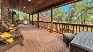 A covered deck with wooden flooring, a grill, and outdoor seating with cushions. - Built for large groups with luxury accommodations - An at home feel for everyone (Happy Jack)