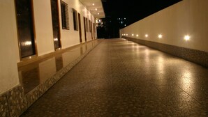 Un pasillo con suelo de baldosas y varias puertas a la izquierda, que conduce a un edificio.