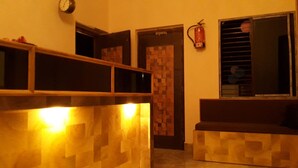 Una zona de recepción con un mostrador de madera, un reloj en la pared y un extintor de incendios montado en la pared.