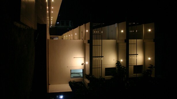 Vista interior de un edificio moderno con varios niveles, que incluye una escalera, un ventanal y varias luminarias.