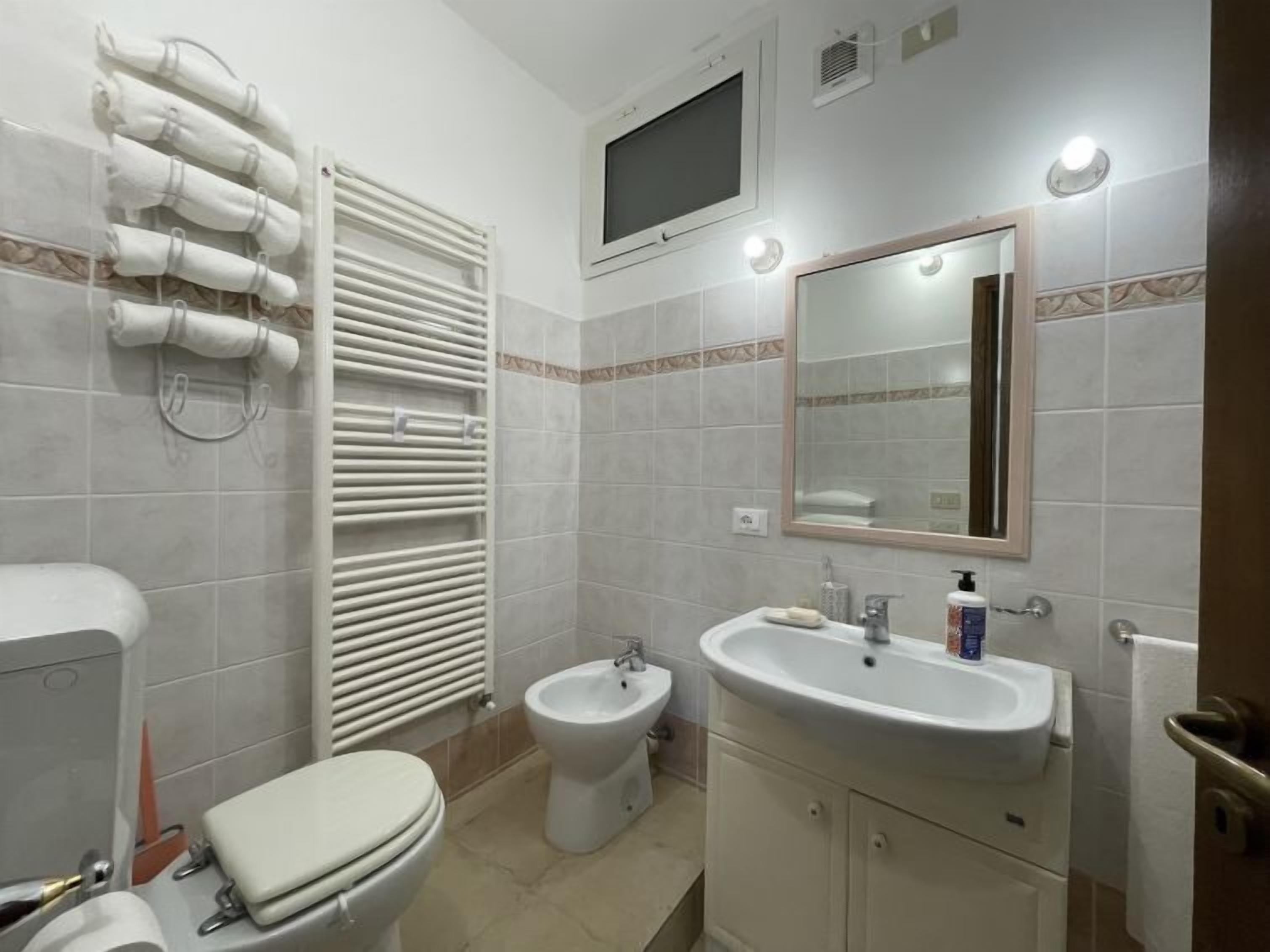 Et badeværelse med toilet, bidet, håndvask og håndklædestang.