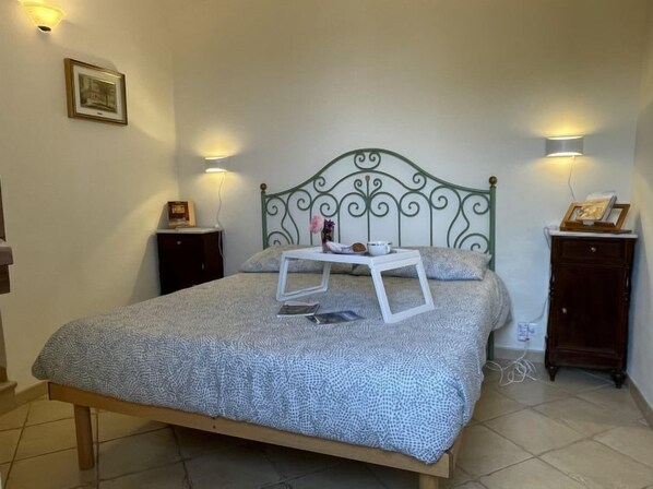 A bedroom with a bed, two bedside tables, and wall-mounted lights.