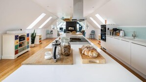 Une cuisine spacieuse de style loft, avec de hauts plafonds, des fenêtres de toit et un îlot central.