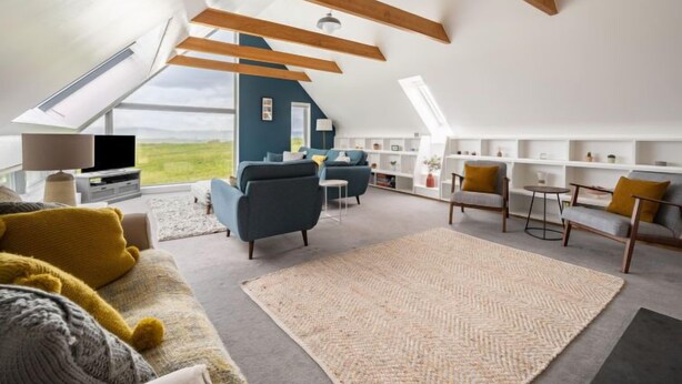 Un vaste appartement de style « loft » avec de hauts plafonds, des poutres apparentes, une grande verrière et une vue sur la campagne.