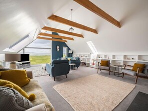 A spacious loft apartment with high ceilings, exposed wooden beams, a large skylight, and a view of the countryside. - Spindrift by Interhome (Isle of Skye)
