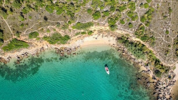 An aerial view of a coastal area with clear turquoise waters, a boat, and rocky terrain. - Apartment Mira by Interhome (Rab/Barbat)