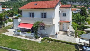 A two-story house with a red-tiled roof, a red awning, and a satellite dish. - Apartment Mira by Interhome (Rab/Barbat)