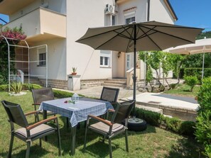 An outdoor patio with a table and chairs, a large umbrella, and a well-maintained garden.