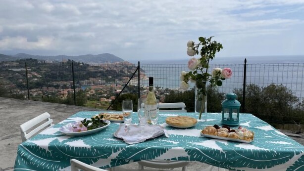 Mesa dispuesta con comida y bebidas, con vistas a un paisaje pintoresco de un pueblo costero.