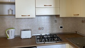 Una cocina con armarios blancos, estufa a gas, hervidor y tostadora.