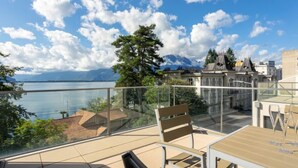 Eine Terrasse mit Blick auf einen See und Berge, ausgestattet mit einem Tisch und Stühlen.