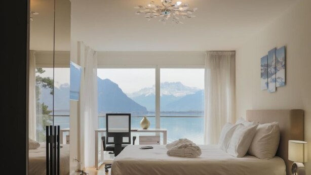 Ein Schlafzimmer mit Bett, Schreibtisch und Blick auf Berge und Wasser.