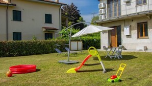 A residential area with a grassy lawn, outdoor furniture, and children's play equipment. - More e Lamponi by Interhome (San Giuliano Terme)