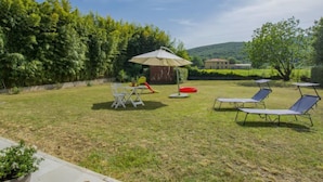 A backyard with a table and chairs, a red circular object, and a white umbrella. - More e Lamponi by Interhome (San Giuliano Terme)