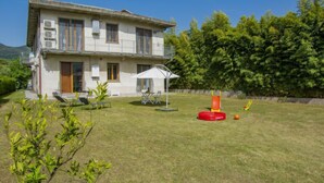 A two-story house with a balcony, a lawn with a play area, and a large tree in the background. - More e Lamponi by Interhome (San Giuliano Terme)