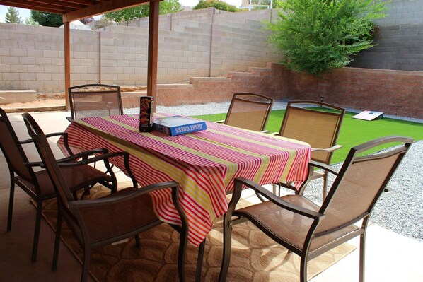 Une terrasse extérieure avec une table dressée pour quatre personnes, entourée de chaises.