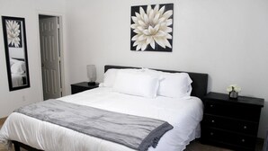 A bedroom with a bed, a nightstand, a dresser, a mirror, and a large flower painting on the wall. - Spacious Escape, 1KB, 2QB, Wifi - Private Yard (Albuquerque)