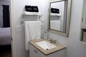 Une salle de bain avec un lavabo blanc, un miroir et deux porte-serviettes avec des serviettes.