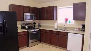 A kitchen with dark wooden cabinets, a black refrigerator, a stainless steel microwave, a gas stove, and a dishwasher. - Spacious Escape, 1KB, 2QB, Wifi - Private Yard (Albuquerque)