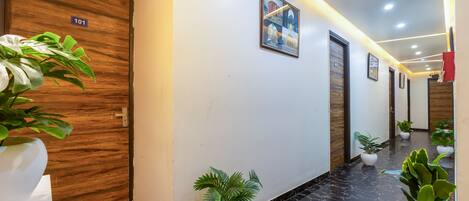 A hallway with wooden doors, numbered 101, and potted plants.