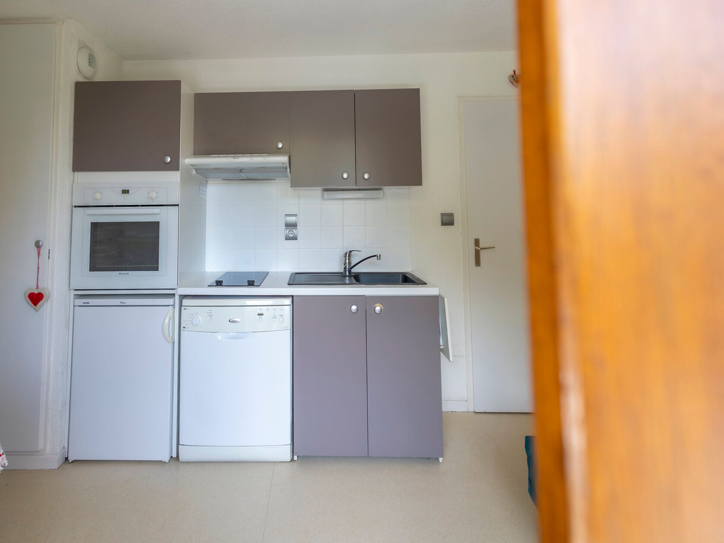 A compact kitchen with a dishwasher, oven, and a sink.