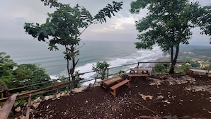 A rocky viewing platform with benches overlooking a coastal area. - Bukit Shoka Top View Camp (Giricahyo)