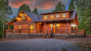 A log cabin with a porch, multiple windows, and a staircase leading to the entrance.