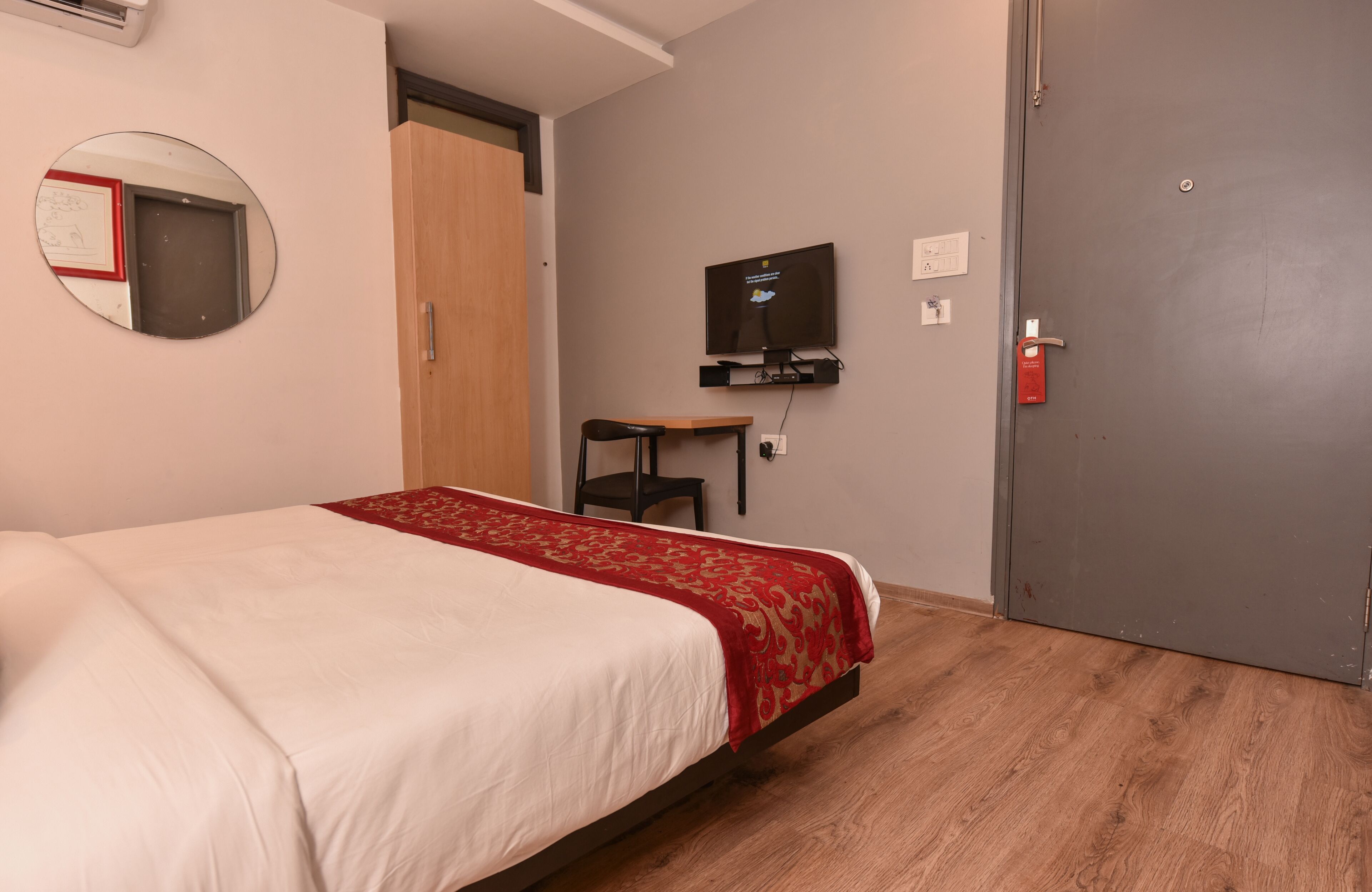 A hotel room with a bed, a television, a small table, and a door.